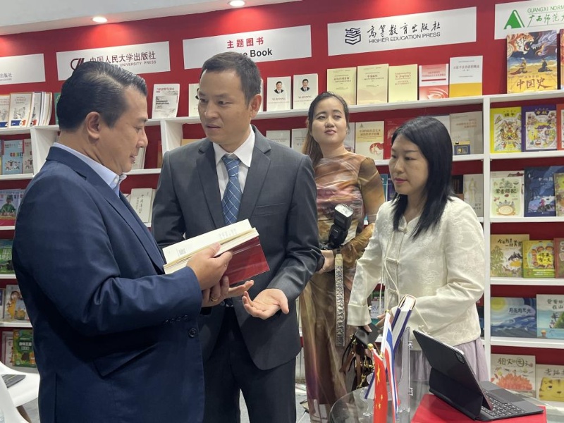 泰国书商和出版商协会主席苏维奇（左一）在翻阅《近镜头：温暖的瞬间》。（卢雯 摄）jpg_副本.jpg